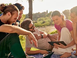Eine Gruppe junger Menschen sitzt im Park zusammen und diskutiert