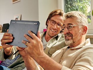 Vater und Sohn schauen auf einen Tablet-Computer.