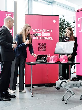 Eine Frau erklärt einer Gruppe von Menschen etwas an einem Laptop