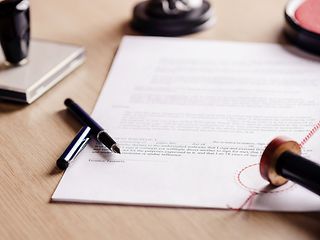 Blatt mit Stift und Stempel auf Tisch
